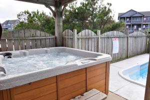 a hot tub in a backyard with a wooden fence at Curlews Call in Nags Head