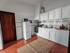 a kitchen with white cabinets and a white refrigerator at apartamentos jardim in Vila Nova de Milfontes