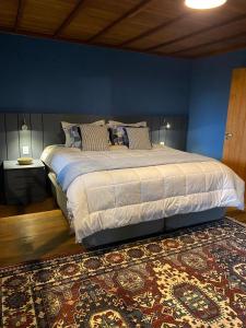a bedroom with a large bed with a blue wall at Yellow House Santa Clara in Bocaina de Minas