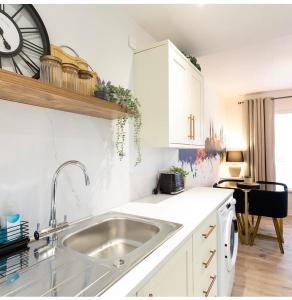 a kitchen with a sink and a clock on the wall at The Belfast Snug in Belfast +6 photos