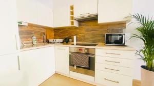 Biała kuchnia z kuchenką i kuchenką mikrofalową w obiekcie Apartament Słoneczny 10 w mieście Opole +32 zdjęcia