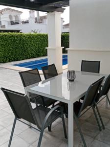 ein weißer Tisch und Stühle mit einem Pool im Hintergrund in der Unterkunft Villa Marrajo La Torre Golf Resort in Torre-Pacheco