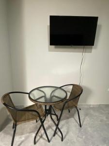a table and two chairs and a television on a wall at Mablia Suite in Ica