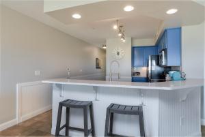 cocina con armarios azules y 2 taburetes en First Flight Retreat 105, en Kill Devil Hills