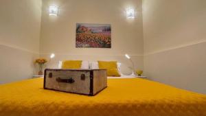 a bedroom with a yellow bed with a box on it at Chez D'Ossuna - Cultura e Relax -10 minuti dalla Cattedrale in Palermo