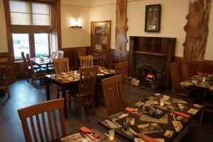 a restaurant with tables and chairs and a fireplace at Buccleuch Arms Hotel in Moffat
