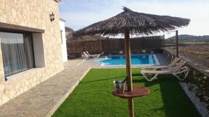 a patio with an umbrella and a swimming pool at Villa El Valle - Piscina climatizada in Tarajalejo