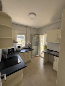 a kitchen with white cabinets and black counter tops at Villa Ohana - A Murcia Holiday Rentals Property in Roldán