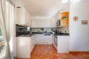 a kitchen with white cabinets and a tile floor at L'Oasis de rêve villa 5 chambre avec piscine in Pibrac