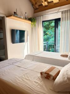 two white beds in a room with a window at Refúgio com Pé na Areia in Mata de Sao Joao +67 photos