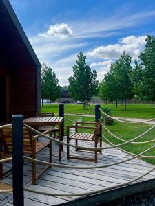 a wooden deck with two benches and a rope fence at Ritopia Glamping in Kovilj +22 photos