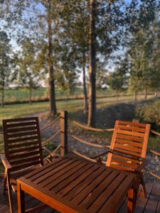 a wooden table and two chairs sitting next to a field at Ritopia Glamping in Kovilj