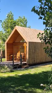 a small cabin with chairs on a deck at Ritopia Glamping in Kovilj
