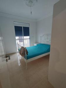 Un dormitorio con una cama con sábanas azules y una ventana. en 2 slaapkamer appartement in alhoceima bades, en Alhucemas 2 fotos más