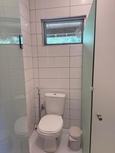 a small bathroom with a toilet and a window at Flat Palmeira-Pipa Solar - centro in Tibau do Sul