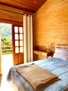 a bedroom with a bed and a large window at Casa em Santo A do Pinhal, vizinha à Campos do Jordão in Santo Antônio do Pinhal