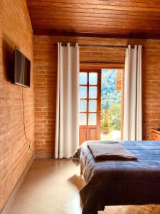 a bedroom with a bed and a tv and a window at Casa em Santo A do Pinhal, vizinha à Campos do Jordão in Santo Antônio do Pinhal