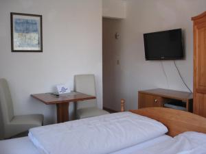 Habitación de hotel con cama, escritorio y TV. en Hotel-Restaurant Cafe Caro en Carolinensiel