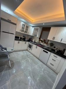 a kitchen with white cabinets and a tile floor at Relax 1 Lüks villa in Kemer