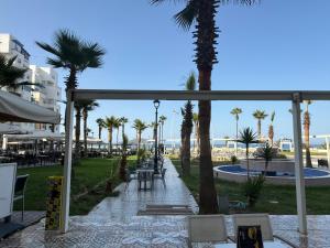 a patio with palm trees and a table and chairs at Alma Martil - Appart face à la plage - plage à 50m - Juste en face! in Martil