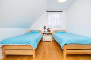 two beds in a bedroom with wooden floors and a window at Domek Bajkowy Zakątek nad jeziorem Narie in Bogaczewo