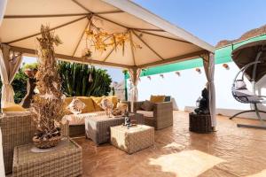 a patio with couches and chairs under an umbrella at Angels Pathway in Fátaga