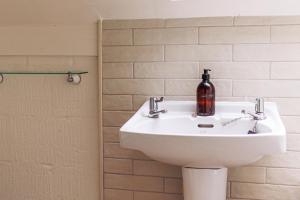 La salle de bains est pourvue d'un lavabo et d'une bouteille. dans l'établissement Dreamy Suffolk Country Cottage Escape, à Aldeby 17 autres photos