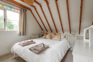 une chambre avec un lit blanc avec deux serviettes dessus dans l'établissement Dreamy Suffolk Country Cottage Escape, à Aldeby