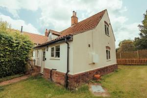 une petite maison blanche avec un toit rouge dans l'établissement Dreamy Suffolk Country Cottage Escape, à Aldeby