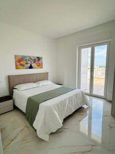 a white bedroom with a bed and a large window at Rooftop Galatina in Galatina
