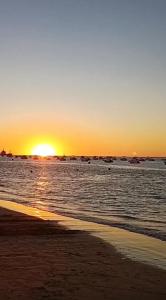 a sunset on the beach with the sun setting at Apartamento Bajo de Guía bajo A in Sanlúcar de Barrameda