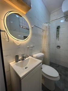 um banheiro com uma pia, um vaso sanitário e um espelho em Azure Villa Suites Apart Hotel em Limbe