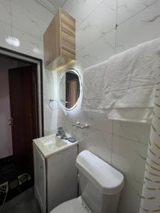 um banheiro com um vaso sanitário, uma pia e um espelho em Azure Villa Suites Apart Hotel em Limbe