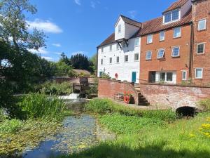 a house and a stream in front of a building at Waterside, Elmham Watermill, Norfolk in North Elmham