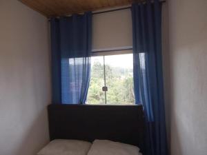 a bedroom with a window with blue curtains and a bed at Casa em Lavras Novas - 2 Suítes casal - AP02 in Ouro Preto