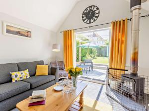 een woonkamer met een bank, een tafel en een klok bij 2 Bed in Bude 82163 in Bude