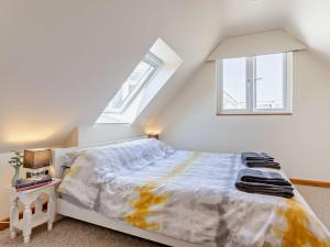 een witte slaapkamer met een bed en twee ramen bij 2 Bed in Bude 82163 in Bude