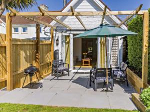 een patio met een parasol, stoelen en een grill bij 2 Bed in Bude 82163 in Bude