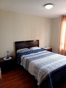 une chambre avec un lit avec une couette bleue et blanche dans l'établissement Cómodo departamento familiar, à Lima