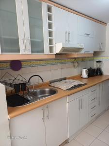 une cuisine avec des armoires blanches et un évier dans l'établissement Cómodo departamento familiar, à Lima