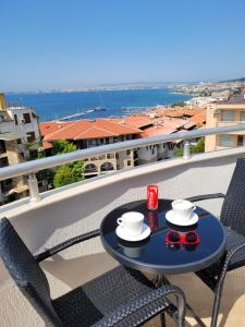 a table on a balcony with a drink and glasses at Ela, Kedar 7 in Sveti Vlas