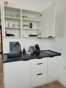 a kitchen with white cabinets and a black counter top at Ela, Kedar 7 in Sveti Vlas