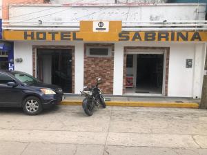 Een motorfiets staat geparkeerd voor een hotel. bij Hotel Sabrina in Cedro