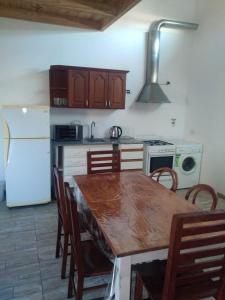 a kitchen with a wooden table and a white refrigerator at Departamento Nuevo Horizonte Pet Friendly in Olavarría