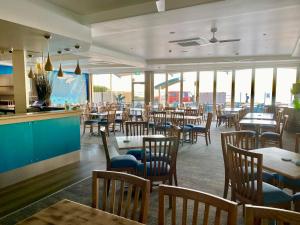 a restaurant with wooden tables and chairs and windows at The Dorsal Boutique Hotel in Forster