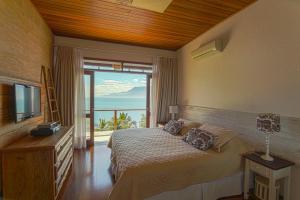 a bedroom with a bed with a view of the ocean at Villa Bermahe in Ilhabela +42 photos