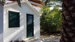 a white building with green shutters on it at Apartments Iličić in Supetar
