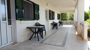 a porch with tables and chairs on a house at Apartments Iličić in Supetar