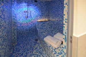 y baño de azulejos azules con ducha y toallas. en Barbarella Suite en Nápoles