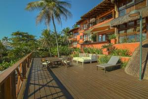 a deck with a table and chairs and a building at Villa Bermahe in Ilhabela